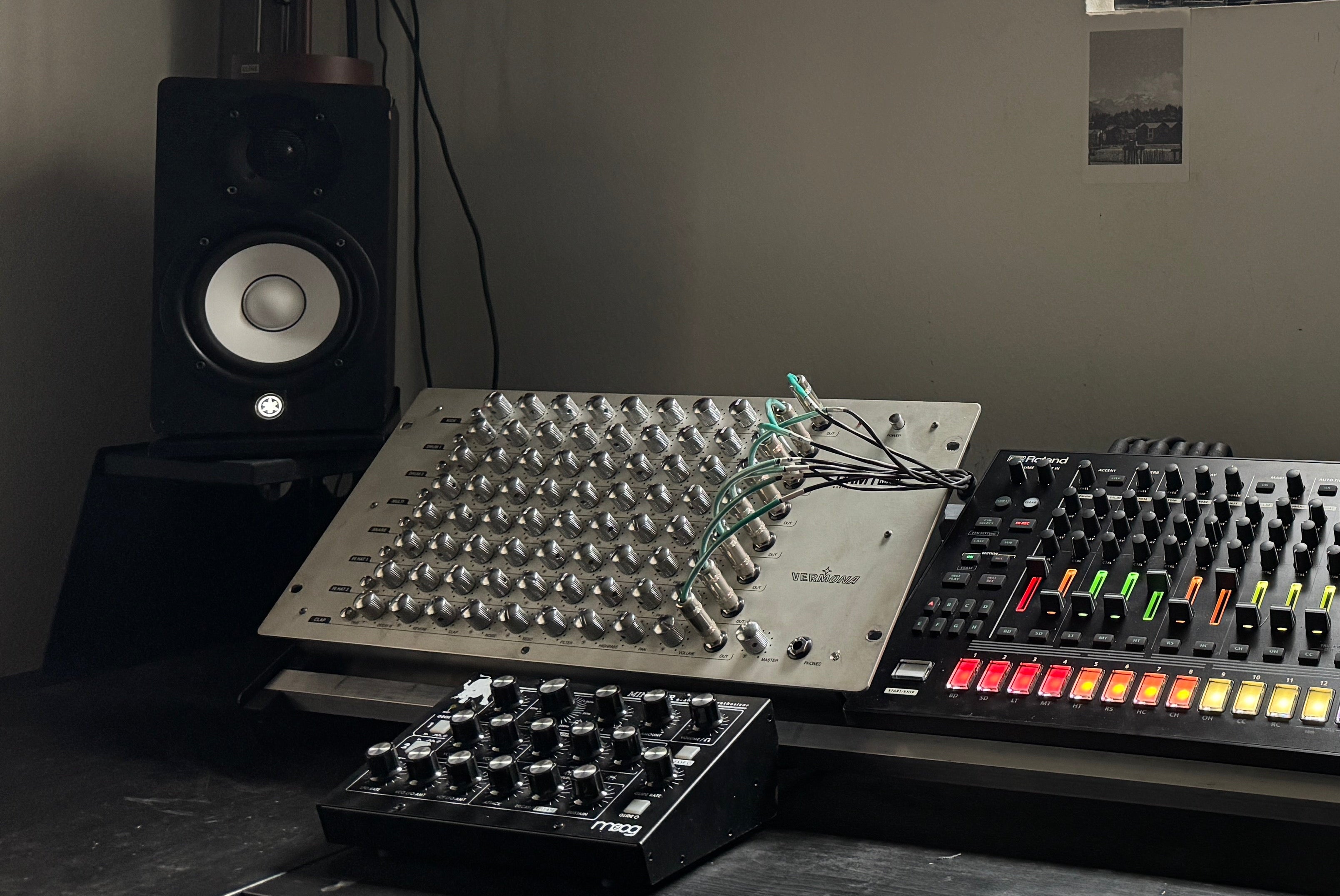 Music production setup with mixing console, keyboard, and speakers in a room with a window.